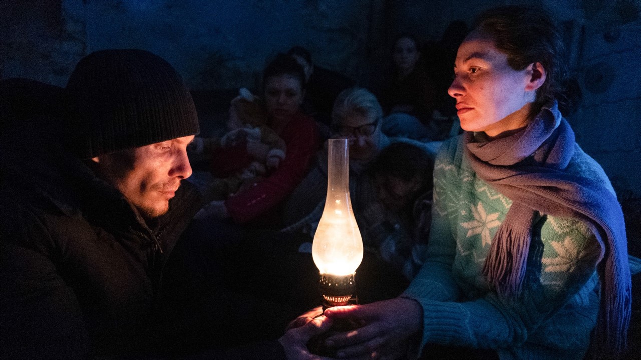 Two people in warm clothing holding a kerosine lam