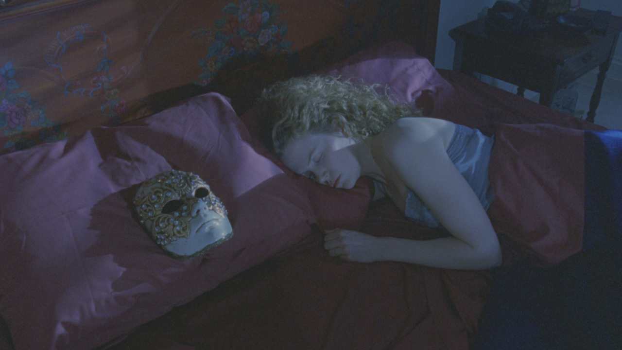 a woman sleeping next to an ornate mask