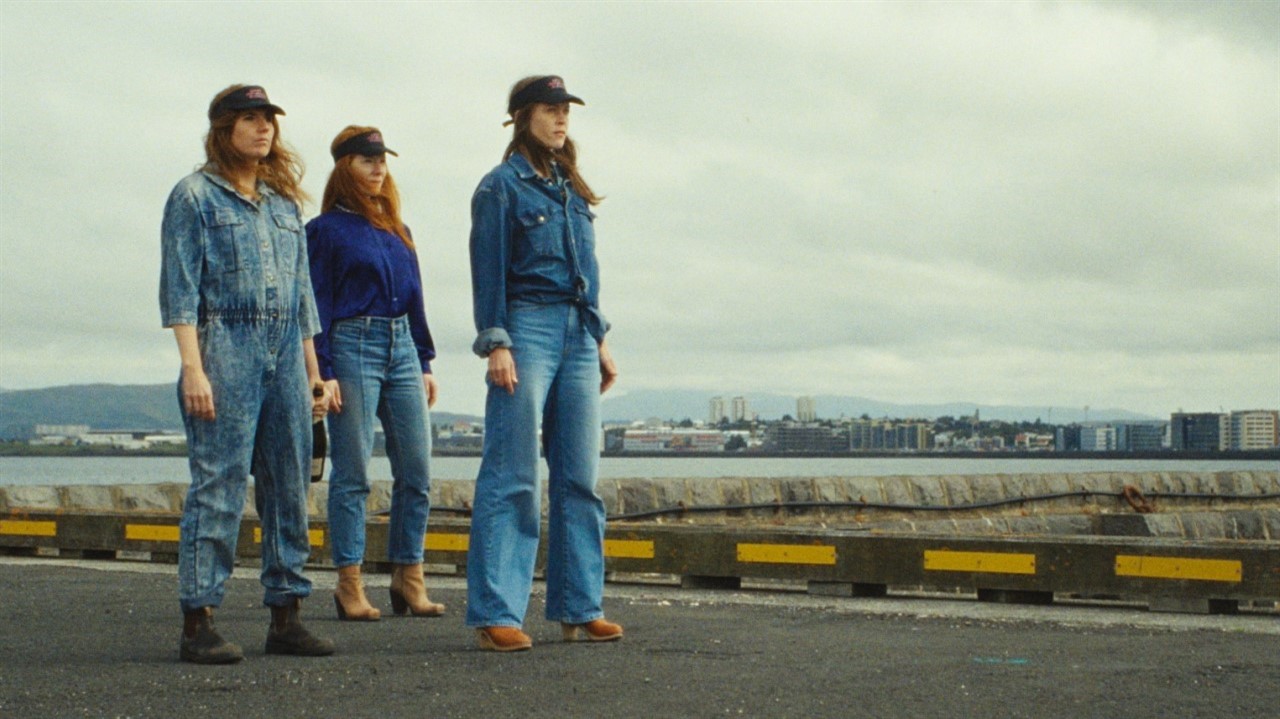 Three women in full-denim outfits standing on a ro