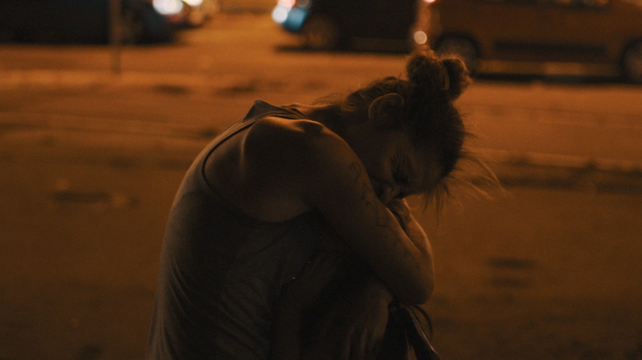 Woman at night outside sitting hugging legs