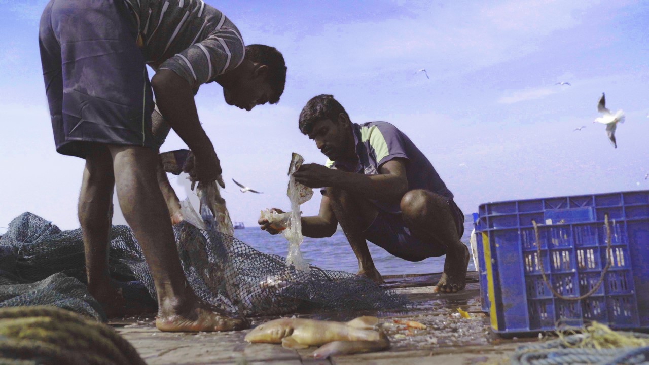 Two fishermen clean trash from their fishing net
