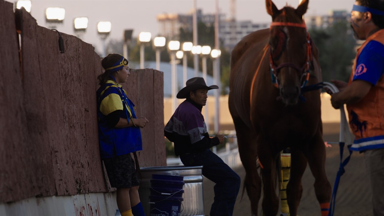 Jockey waits beside a horse.