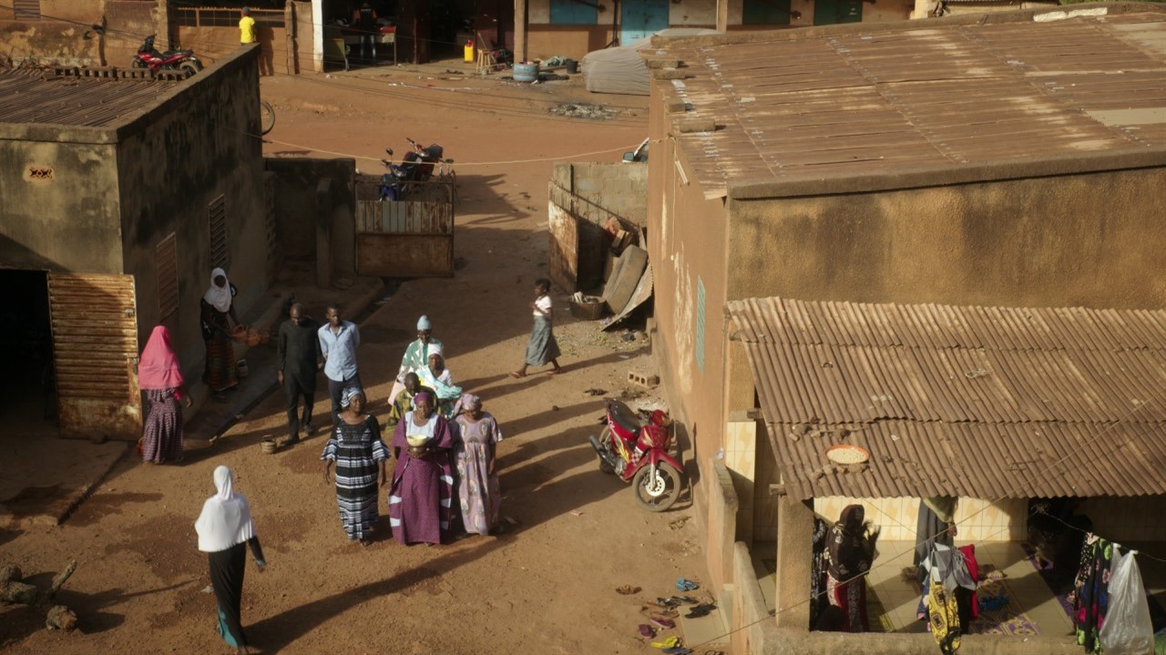 Group of peple in the middle of a dirt road beside
