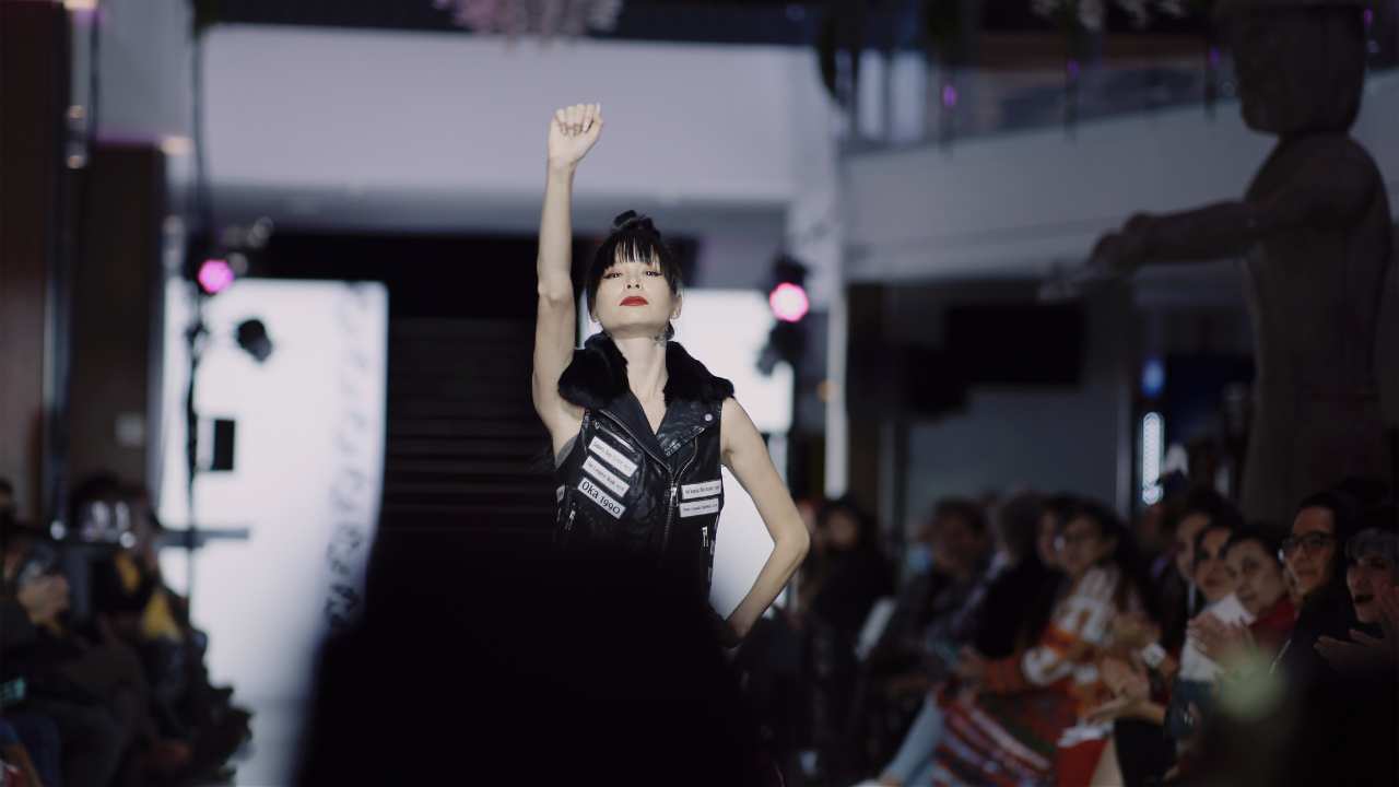 a woman on a runway with one arm raised in the air