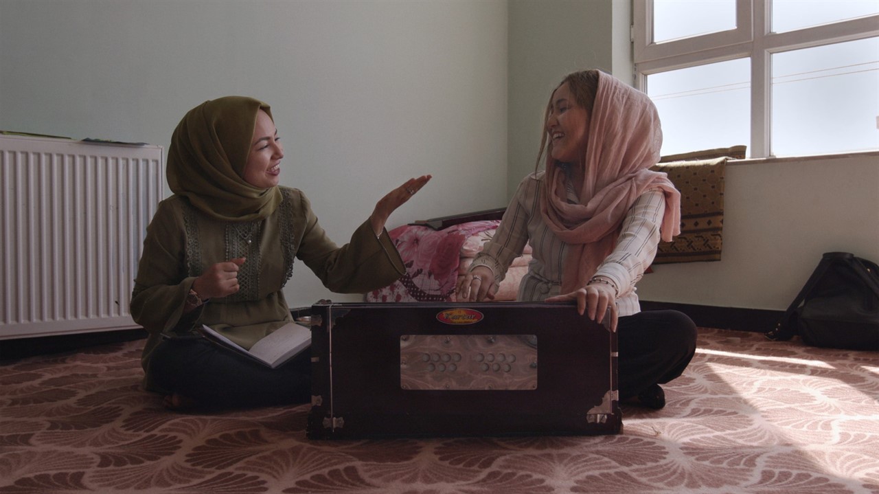 Two Women sit on floor with instrument case