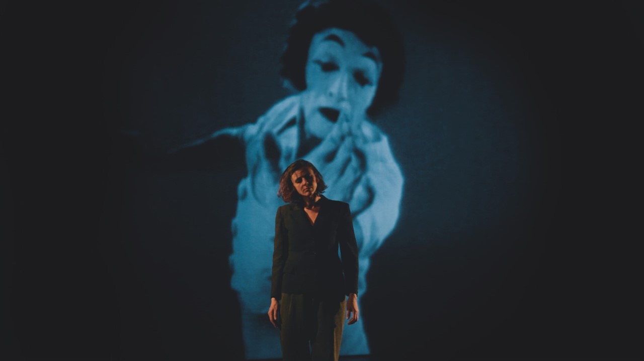 Woman in a blazer in front of a projected film
