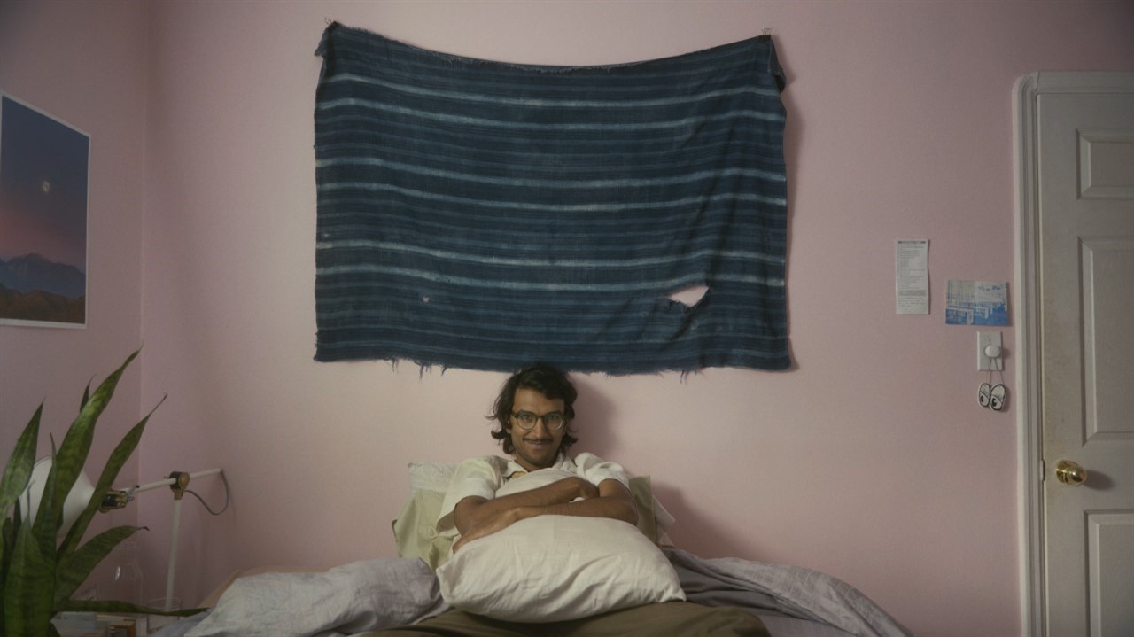 Man with glasses sitting on a bed