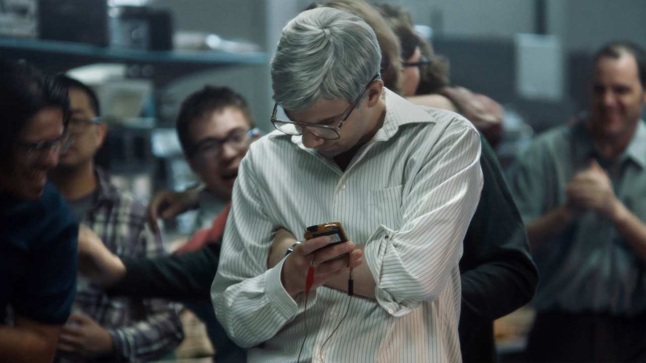 a man with glasses looking at a device