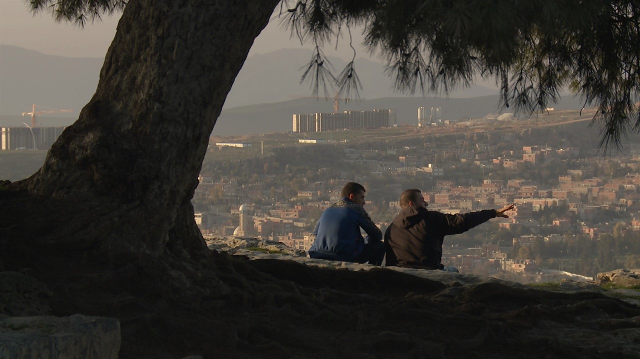 Two Algerian men sitting on a hill talking