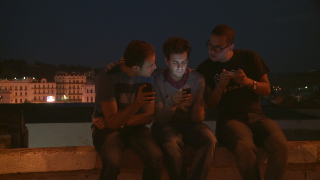Three Algerian men talking and texting