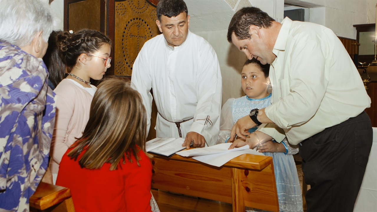 Kid signing documents watched by family