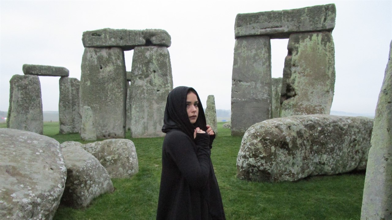 A woman in a hooded cloak at Stonehenge