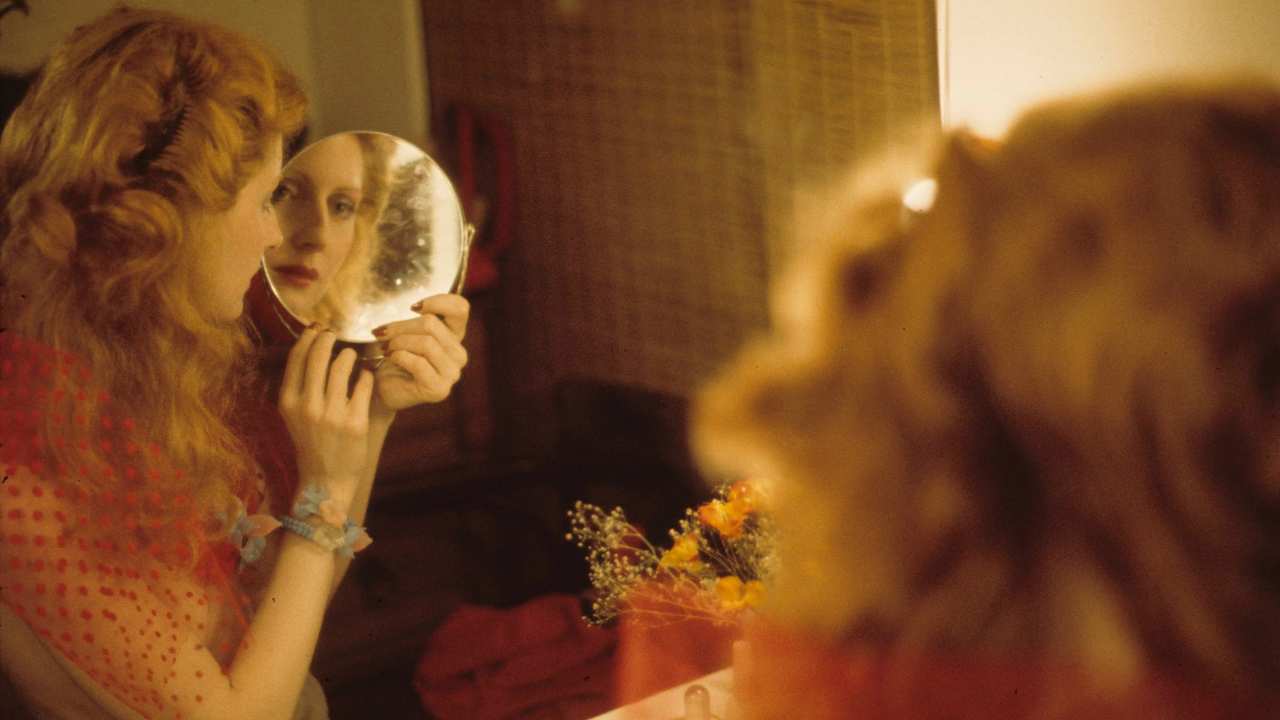 a woman looking at herself in a hand mirror