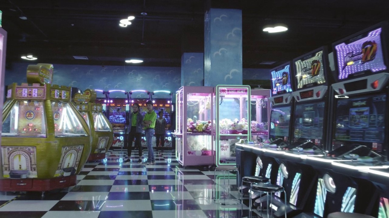 Three people standing in an arcade