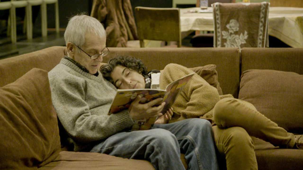 a man and woman cuddling and reading on a couch