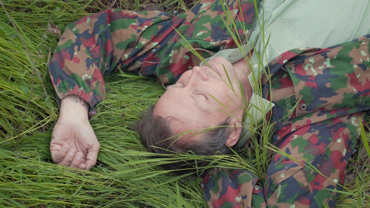 Man in camo jacket lying in a field