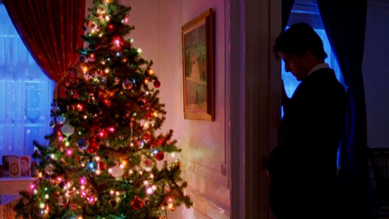 a man standing in the shadows by a Christmas tree