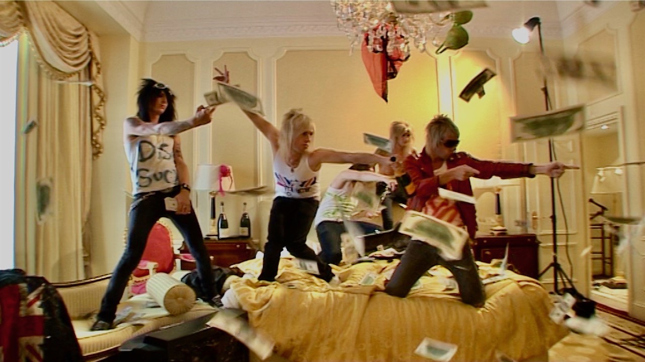 Musicians jumping on bed in hotel room with money 