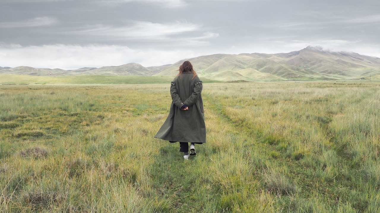 a person in a long coat walking in a field