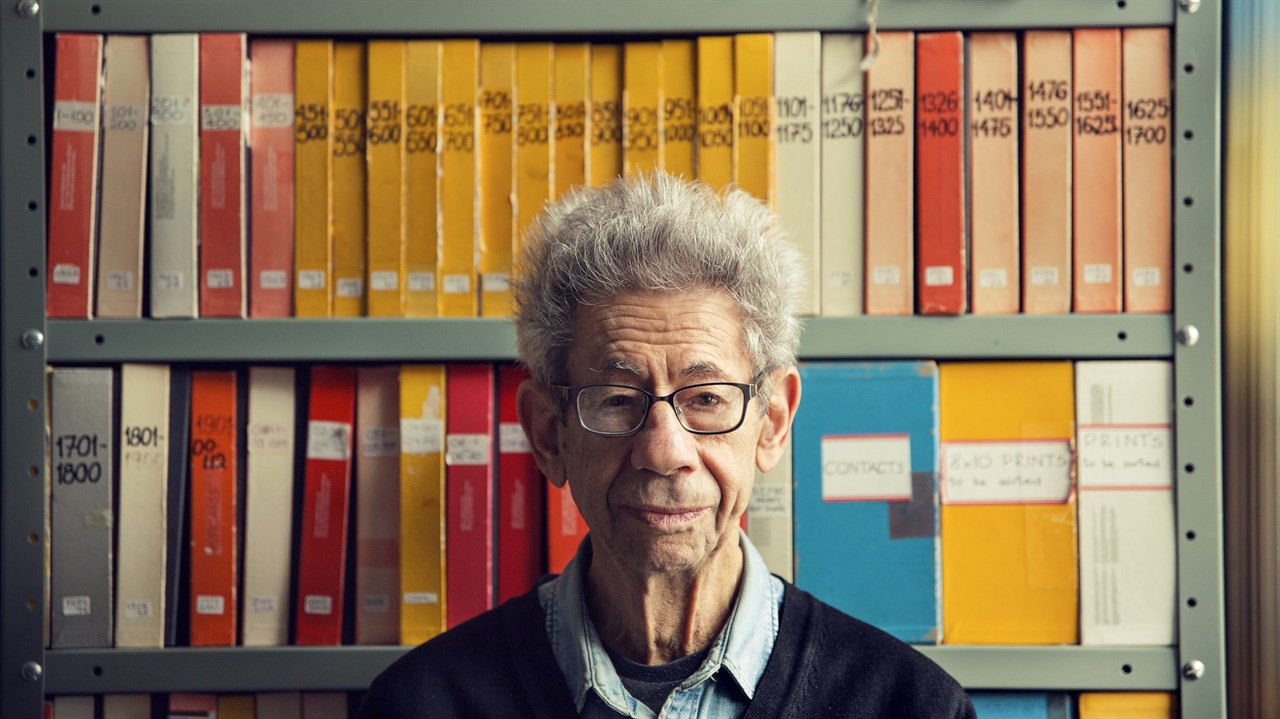 Man with glasses in front of shelves of binders