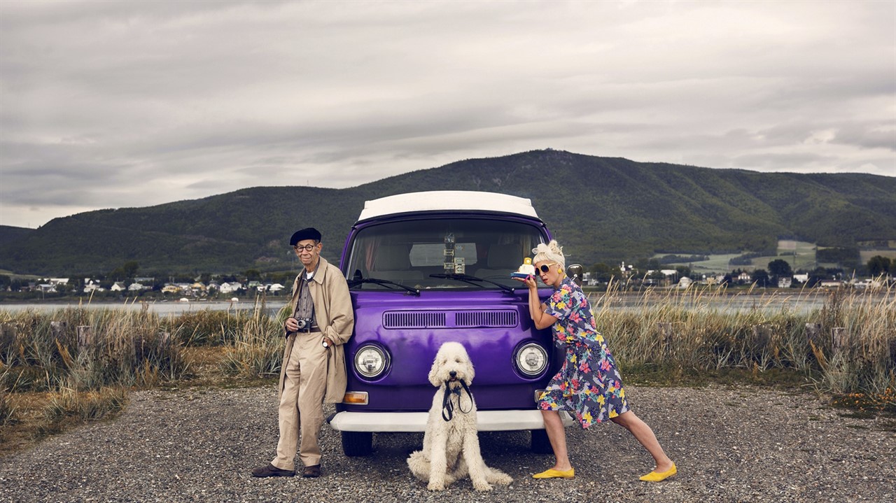 Man, women and dog posing in front of a van