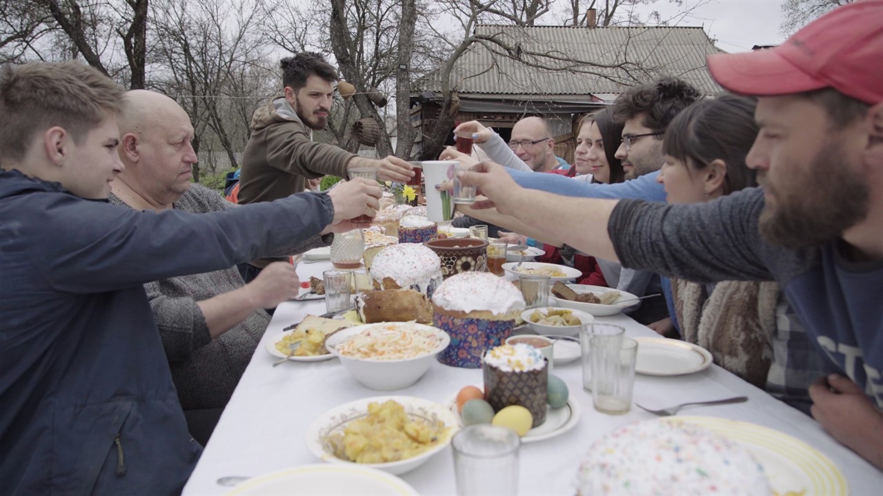 A large group of people toast over a table full of