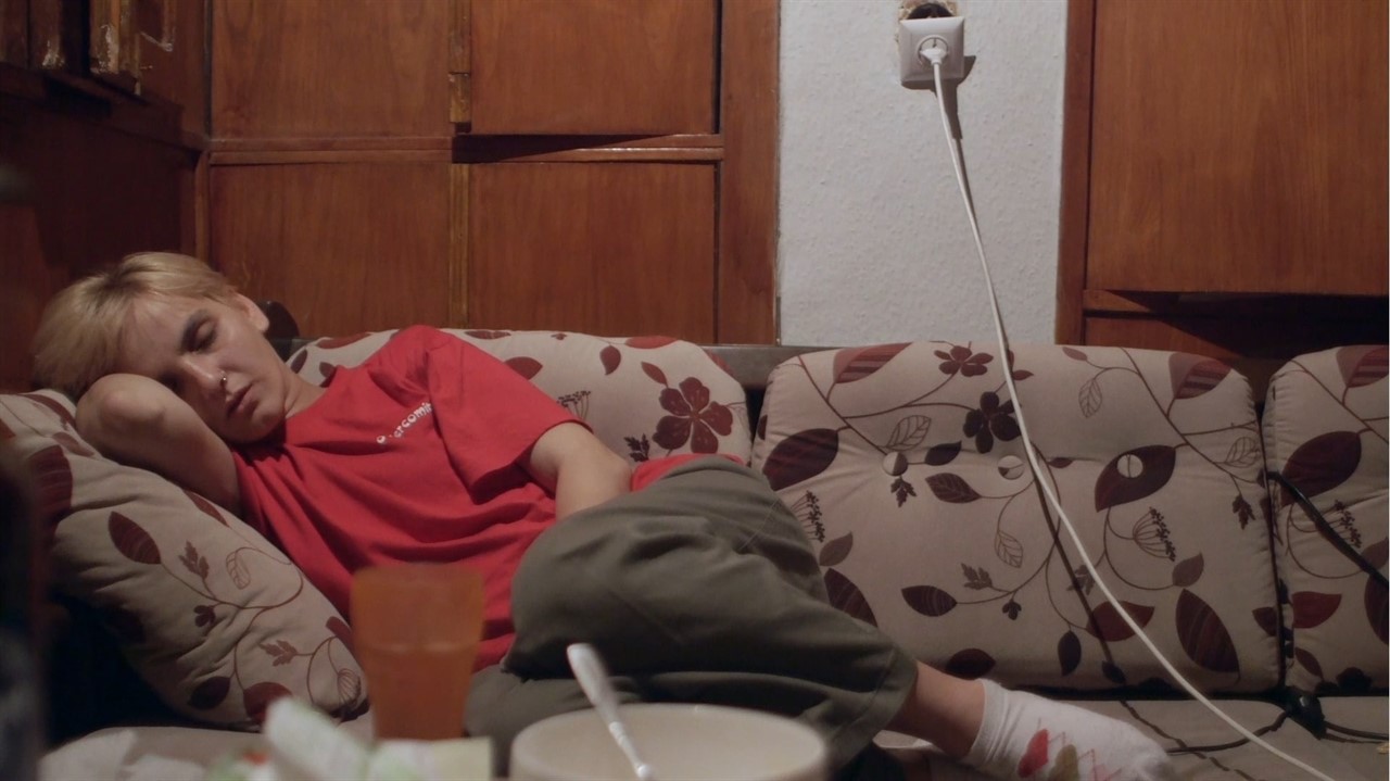 A person laying down on a couch, a cup and bowl on