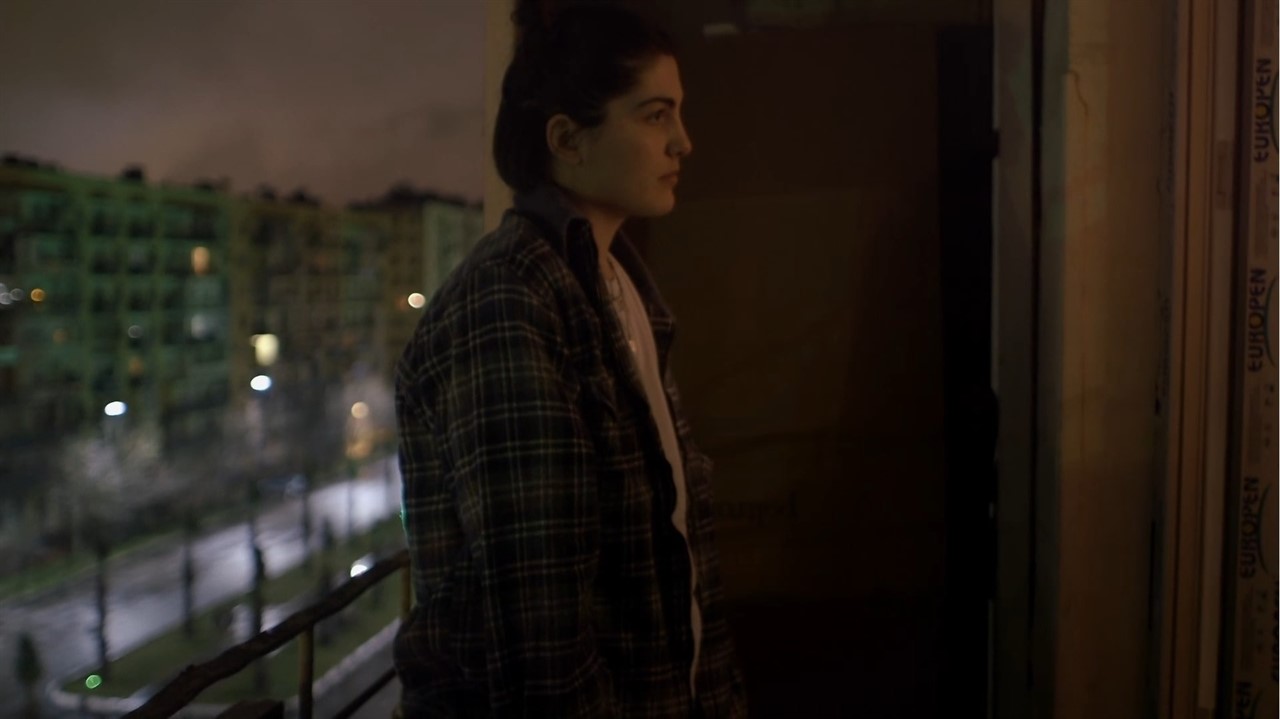 A person in a flannel shirt standing on a balcony.