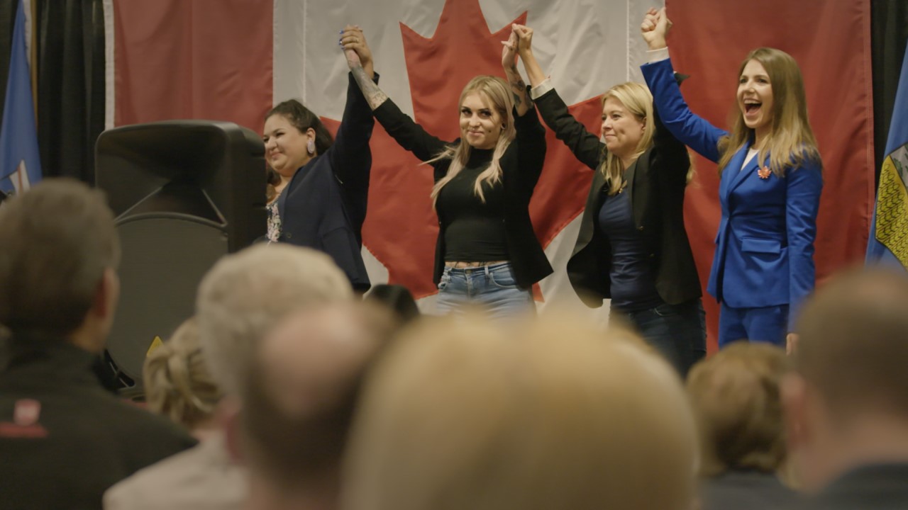 Women holding hands in front of Canadian flag