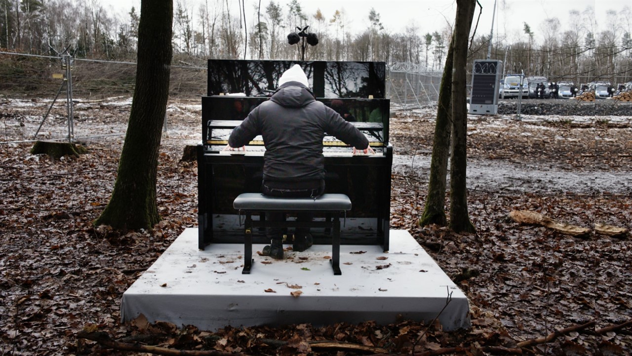 Igor Levit sits at a piano in the middle of a park