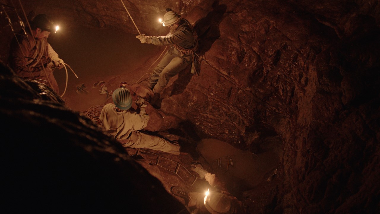 Four people with helmets and ropes in a cave