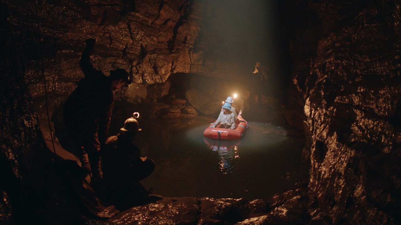 Four cavers crossing an underground lake in a boat