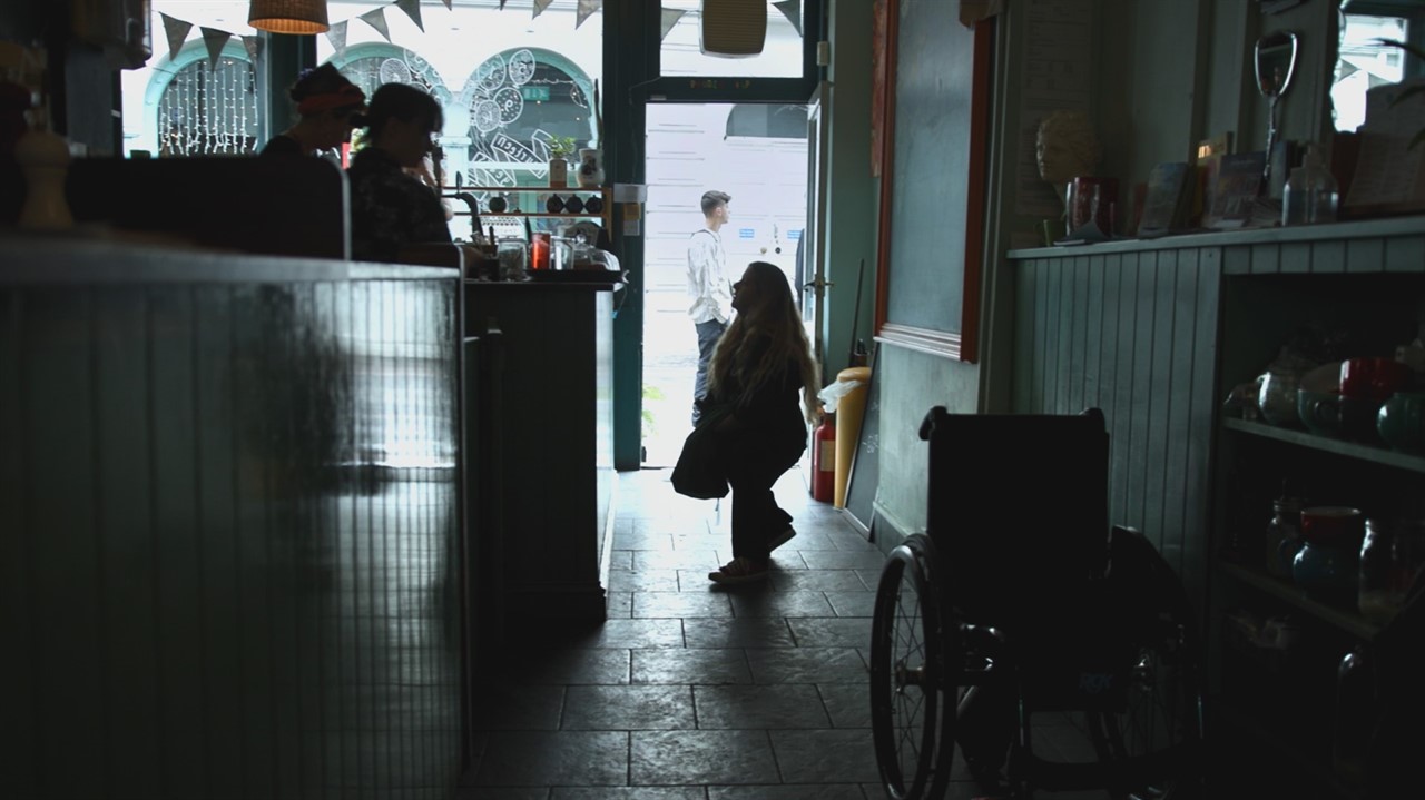A very short woman approaches a counter in a cafe