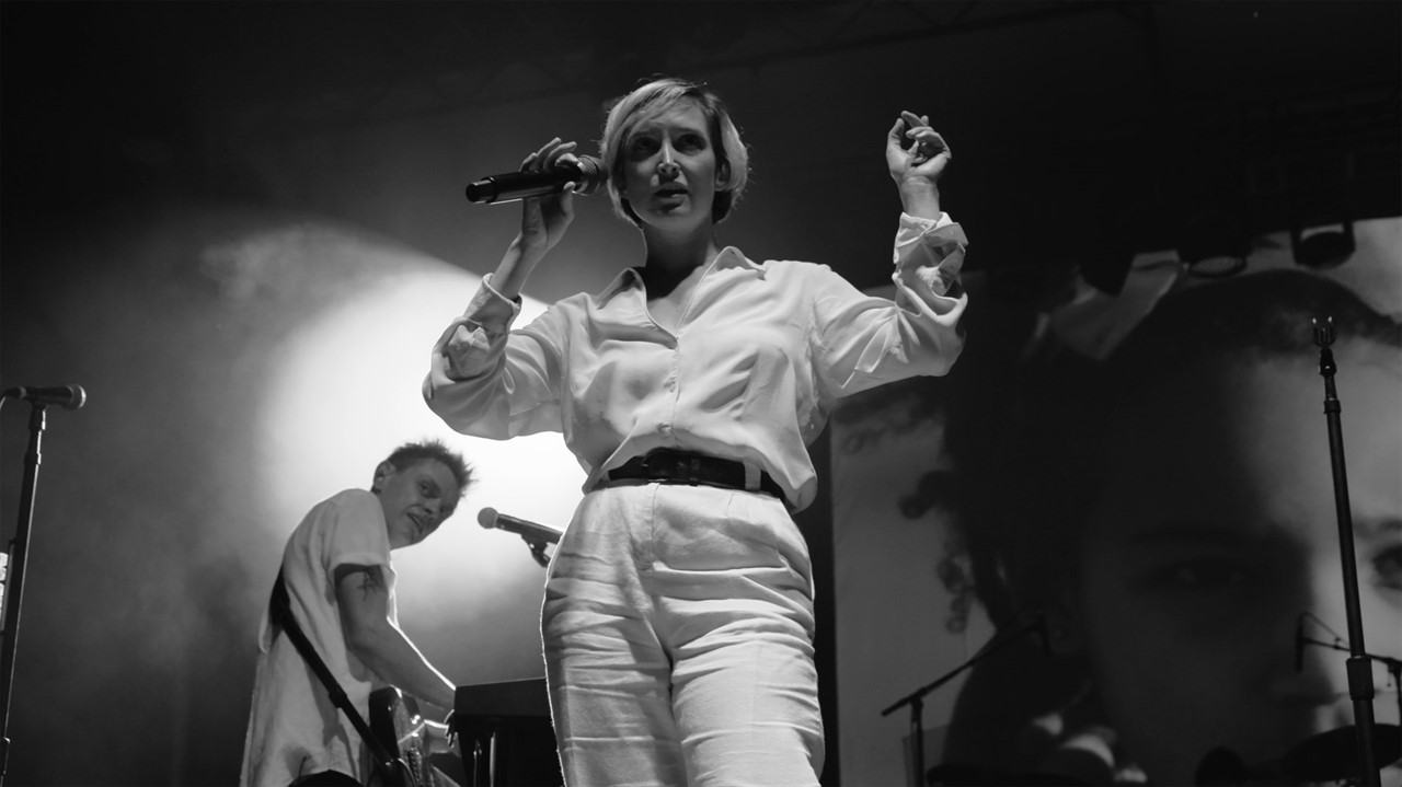 Lead singer of July Talk stands on stage with a mi