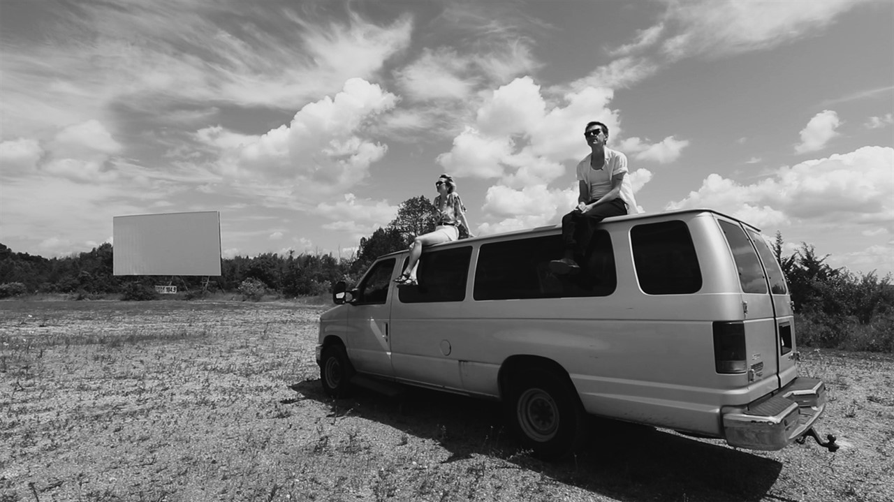 Members of July Talk sit on the top of a van with 