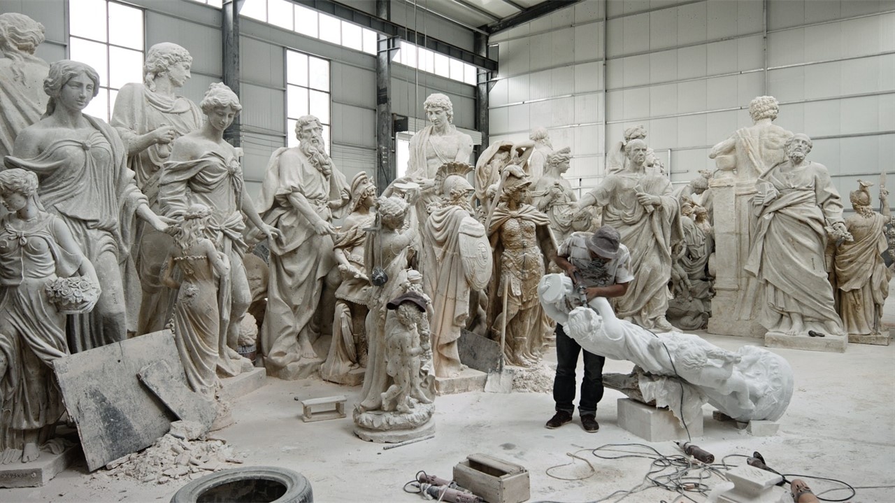 Several statues standing in a warehouse, with a ma