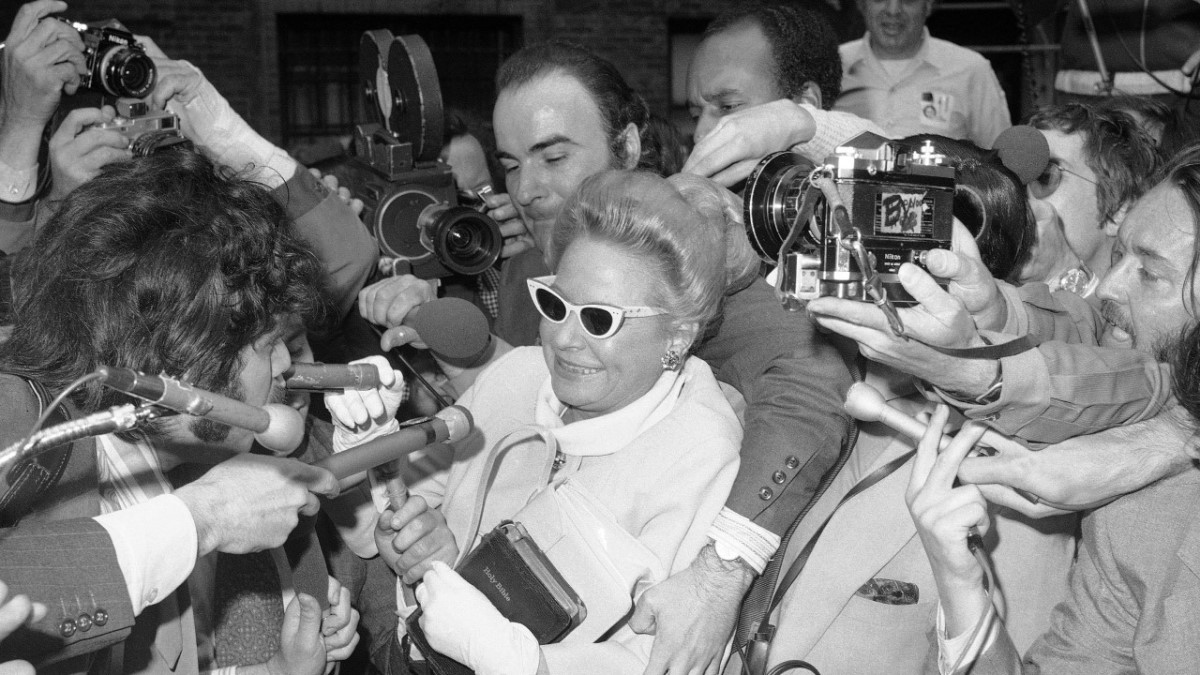 Martha Mitchell smiling at the press swarming her