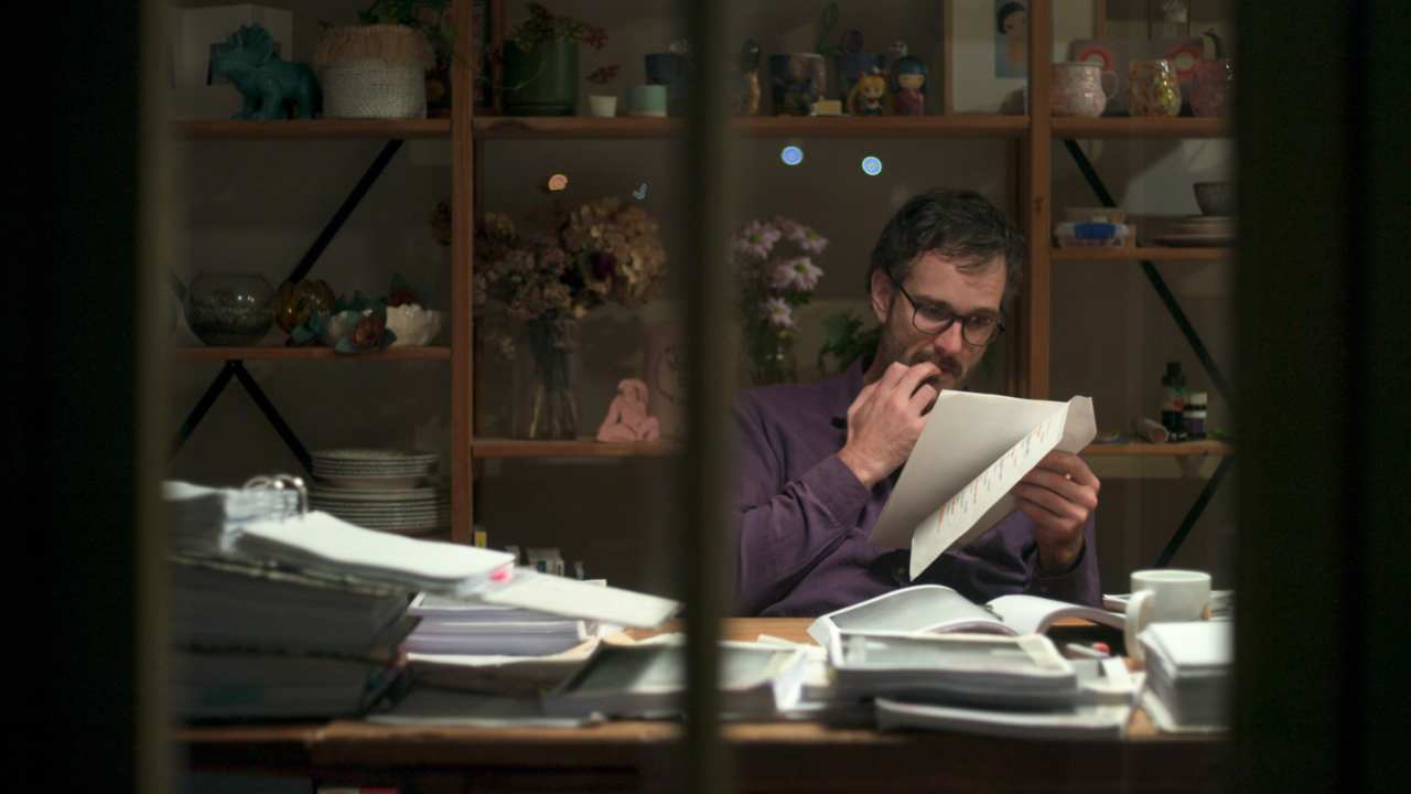 a man with glasses and a beard reading paperwork