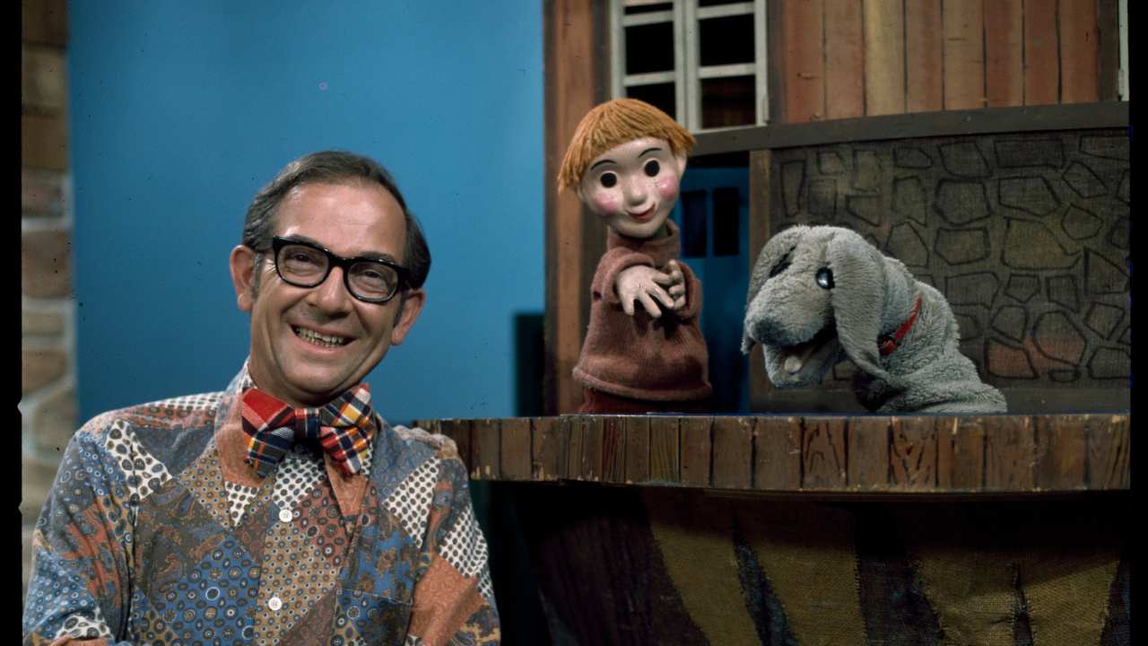 a man with a child and dog puppets