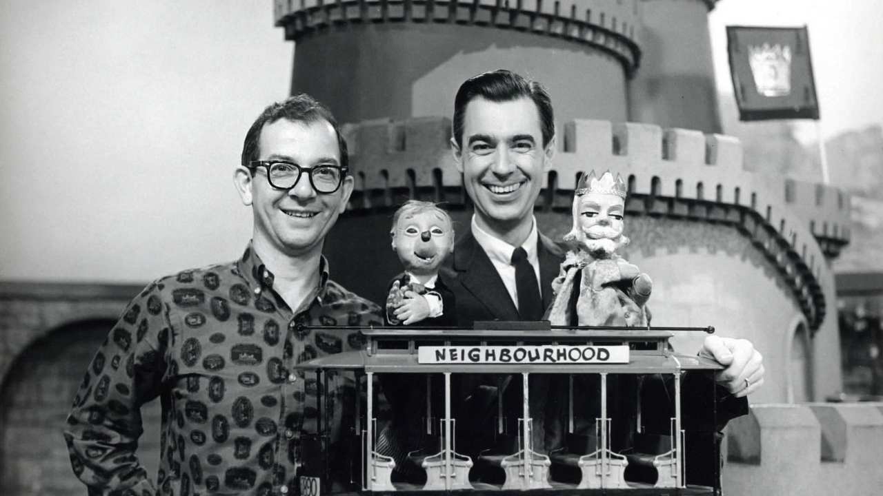 two men and two puppets behind a trolley