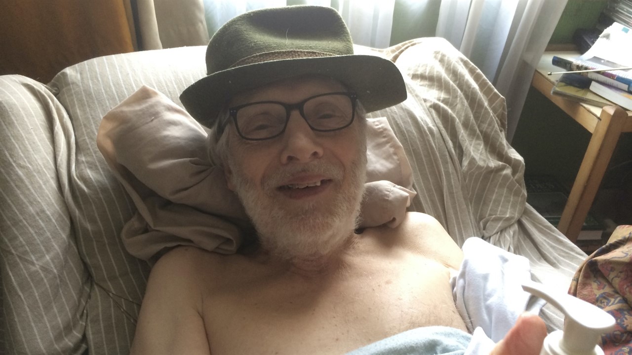 an elderly man with a hat, glasses and no shirt