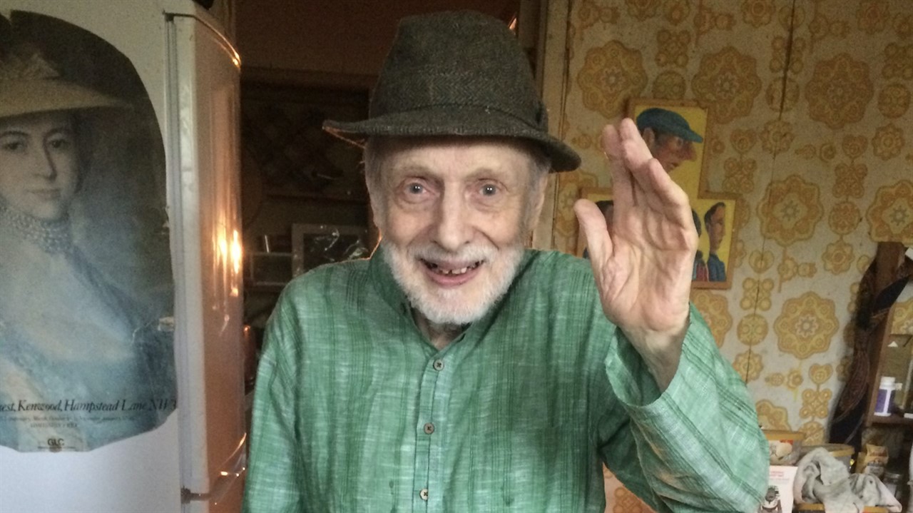 An elderly man in a knit hat and button up shirt