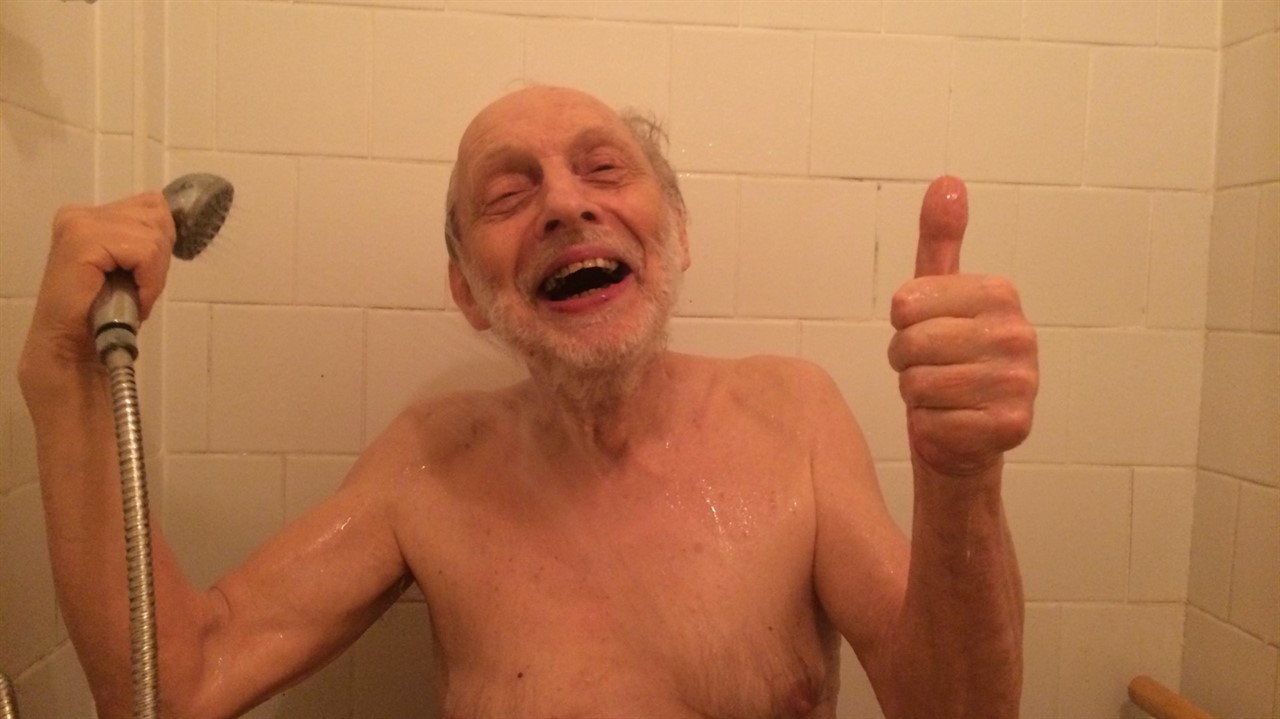 An elderly man smiling in the shower