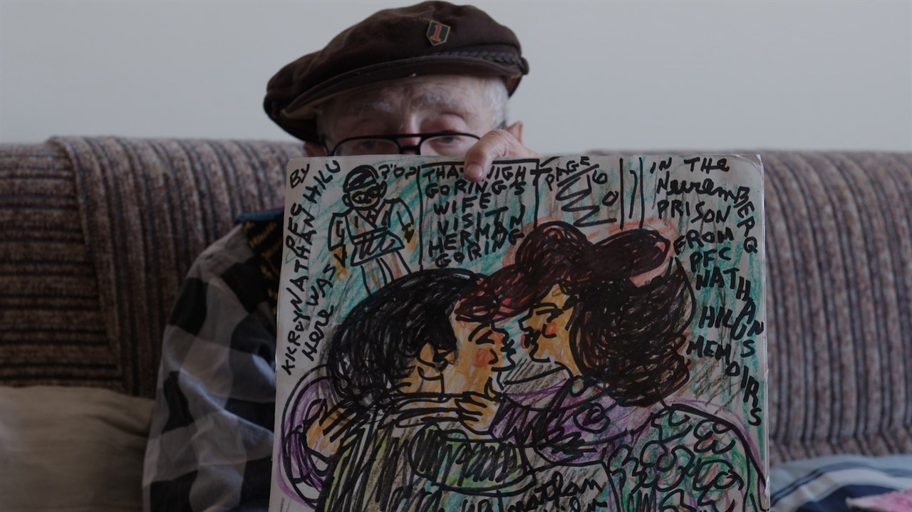 Elderly man holds up handdrawn art