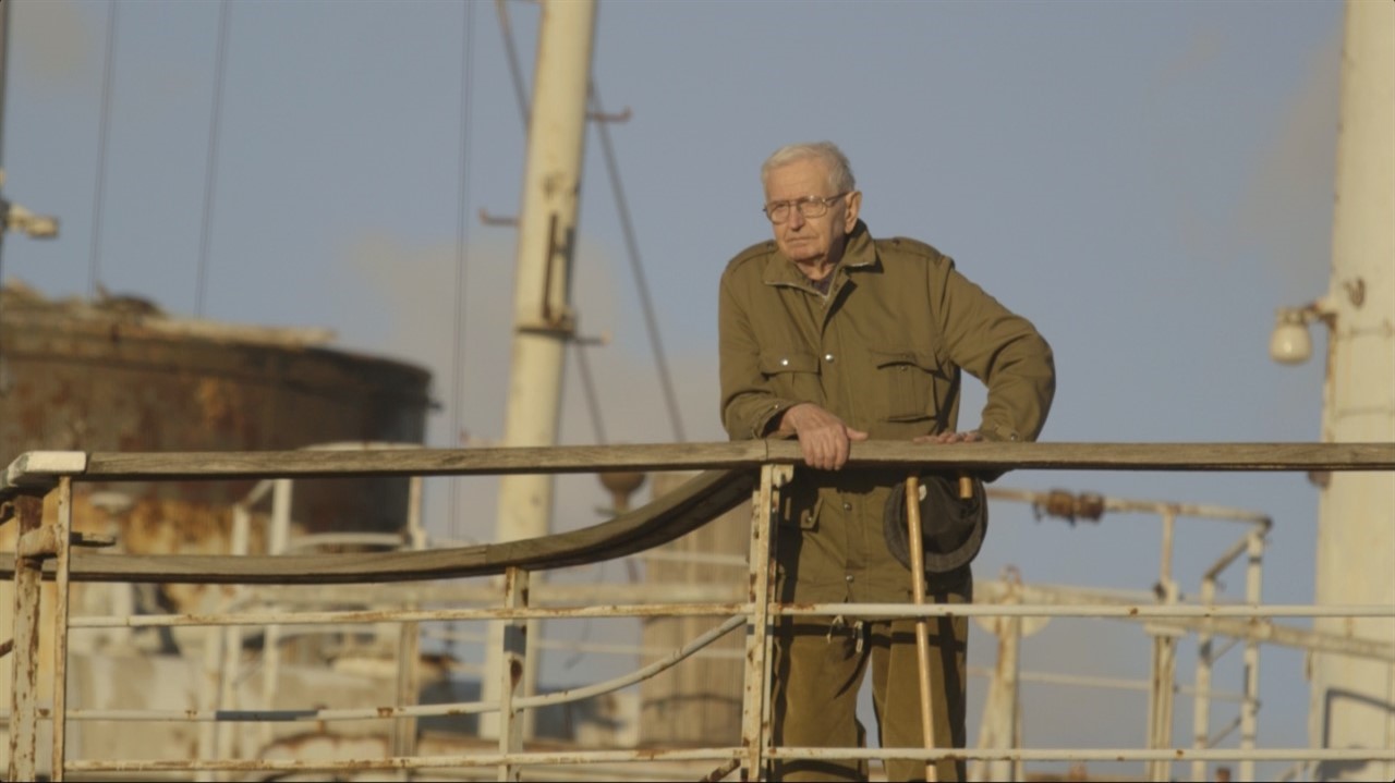 Elderly man leans on the railing of a ship