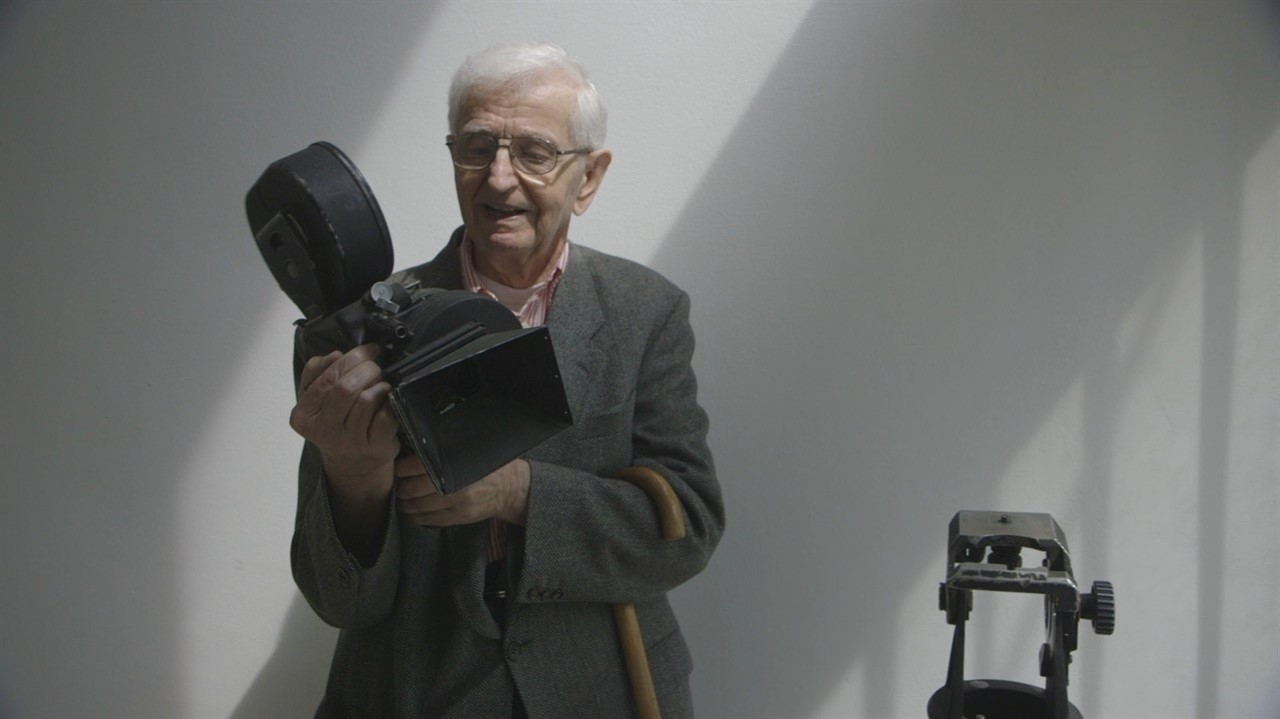 An old man examines an old fashioned film camera
