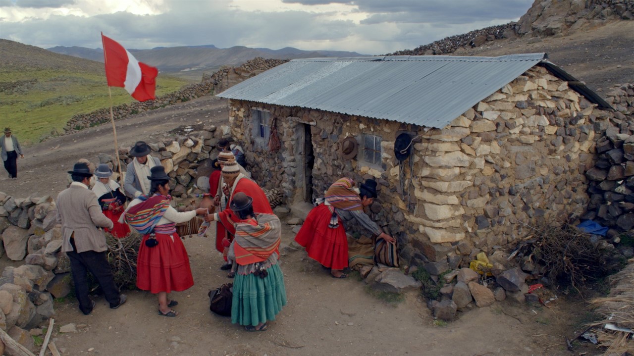 Peruvian people in front of a small stone dwelling