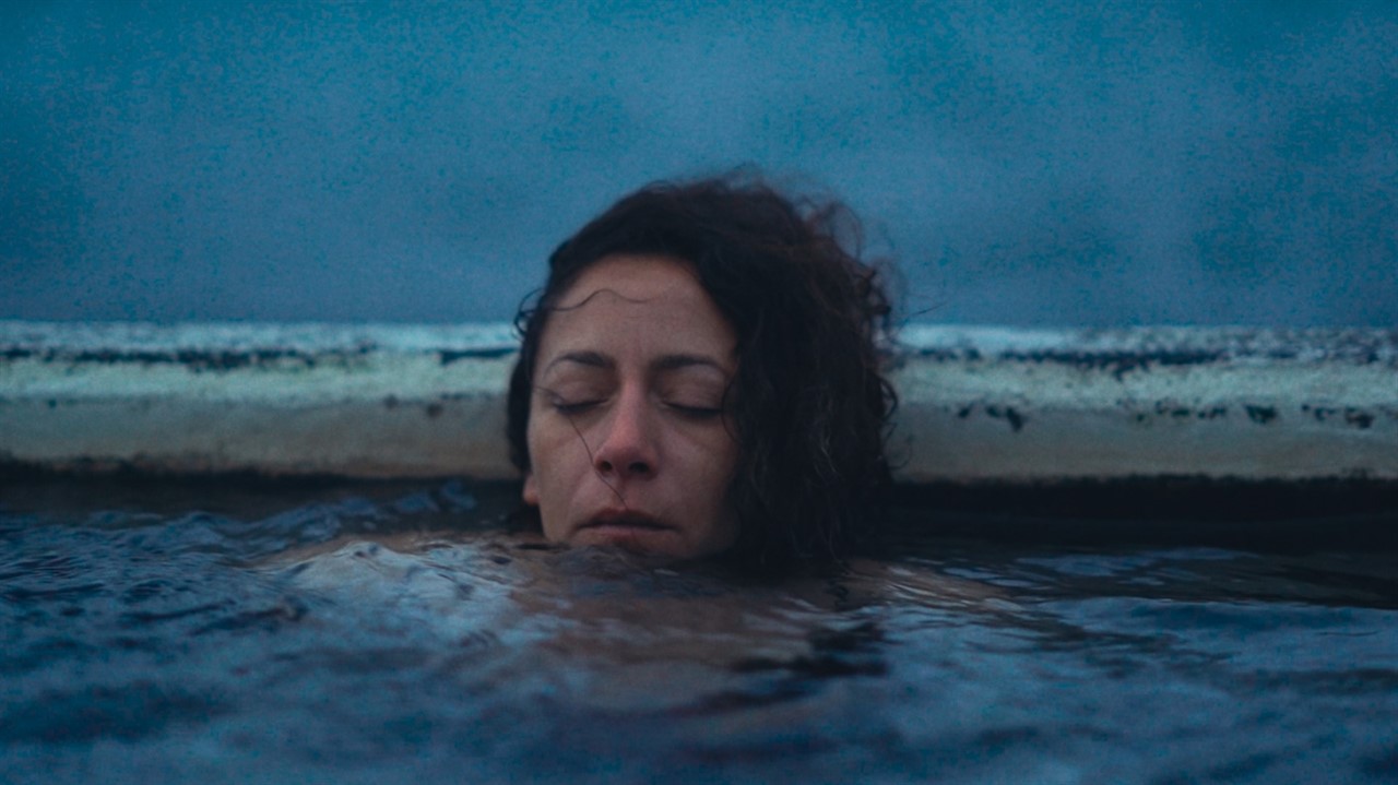 A woman with long hair submerged in water up to he