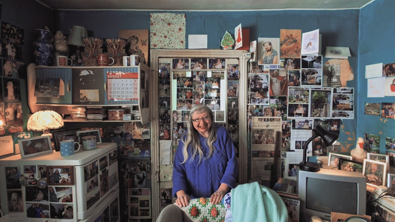 Woman stands in room covered in photographs