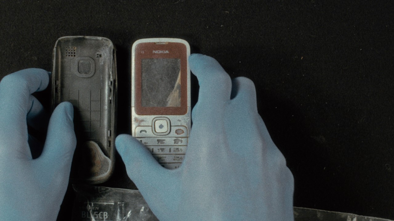 Gloved hands handle broken cell phone